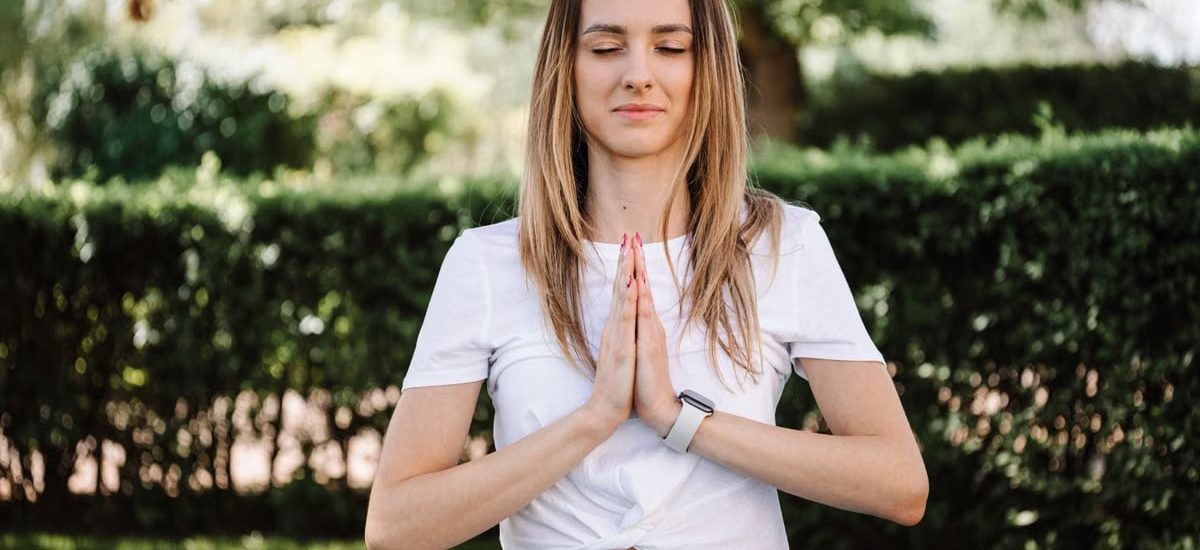 A serene moment of a woman practicing yoga with namaste pose outdoors, embracing mindfulness.
