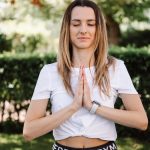 A serene moment of a woman practicing yoga with namaste pose outdoors, embracing mindfulness.