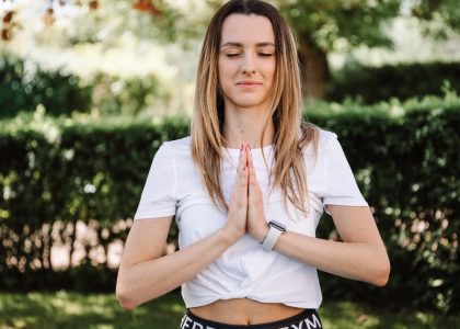 A serene moment of a woman practicing yoga with namaste pose outdoors, embracing mindfulness.